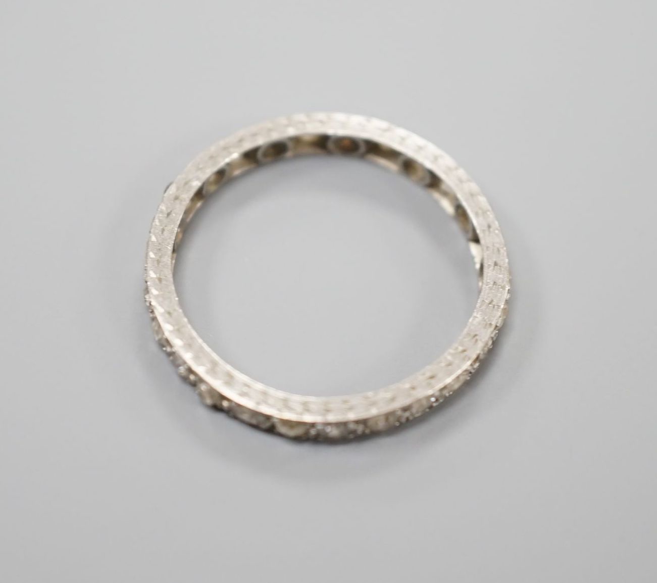 A white metal and diamond chip set full eternity ring, size M, gross weight 2.1 grams.